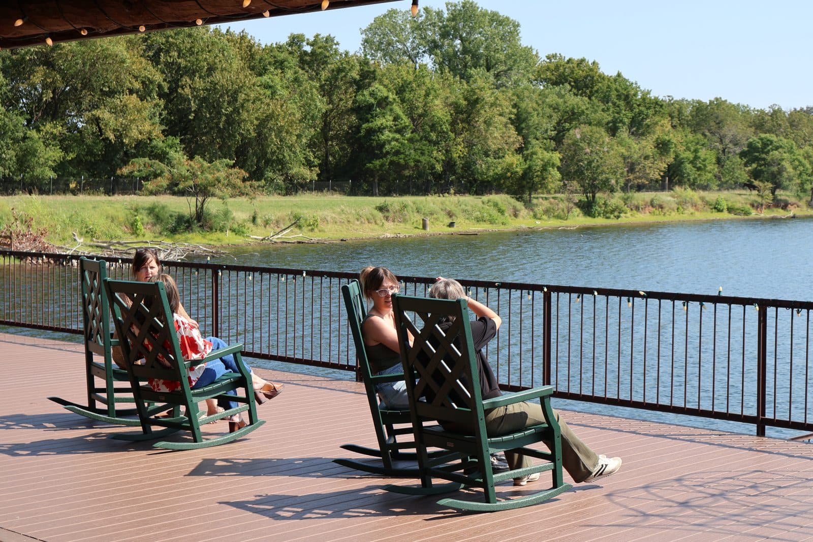 Two women in rocking chairs by the water during a retreat break
